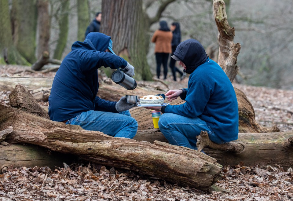 Friends in a bubble stop to enjoy a birthday cake and a warm drink while out walking in Richmond Park, South West London this afternoon