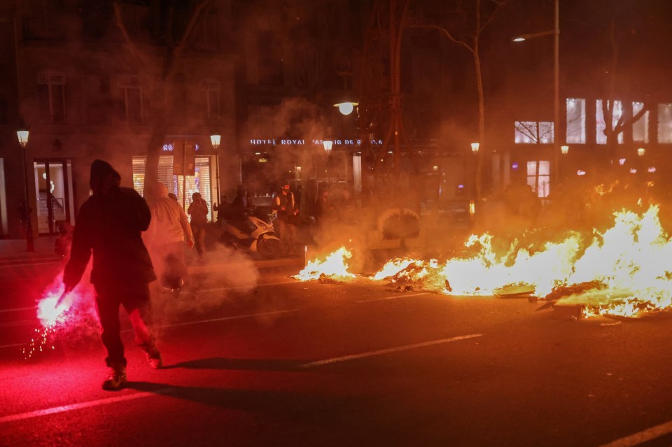 Protesters lit flares behind the flaming barricades in Barcelona