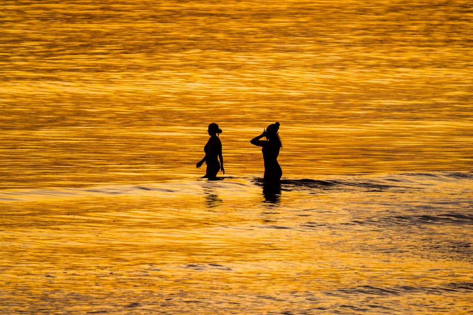 Two swimmers go for a morning dip as the sun rises this morning in Whitby, North Yorkshire