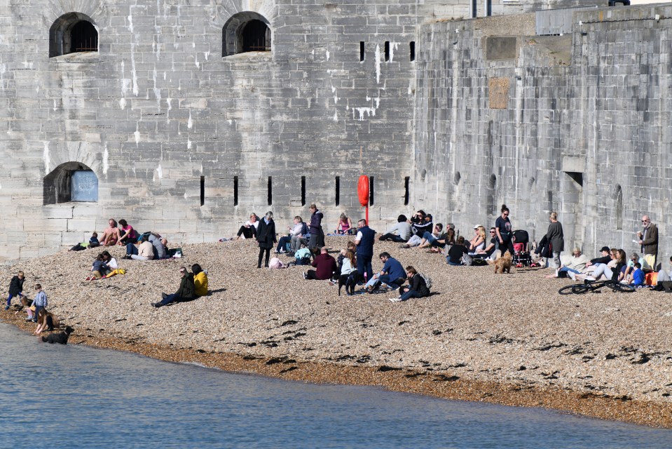 People enjoying the warm weather in Portsmouth, Hampshire on the beach at the Hot Walls in Old Portsmouth