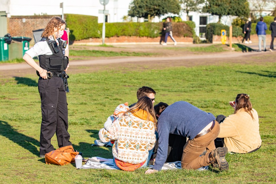 An officer speaks to a group of friends enjoying the mild temperatures on Wimbledon Common