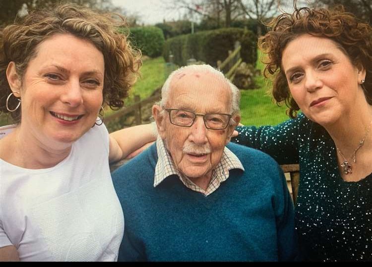 two women are posing for a picture with an older man .