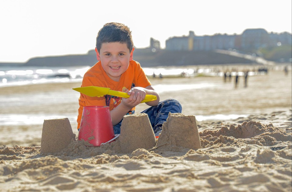 Eight-year-old Harrison Walker building sandcastles in the sun on Tynemouth beach near Newcastle