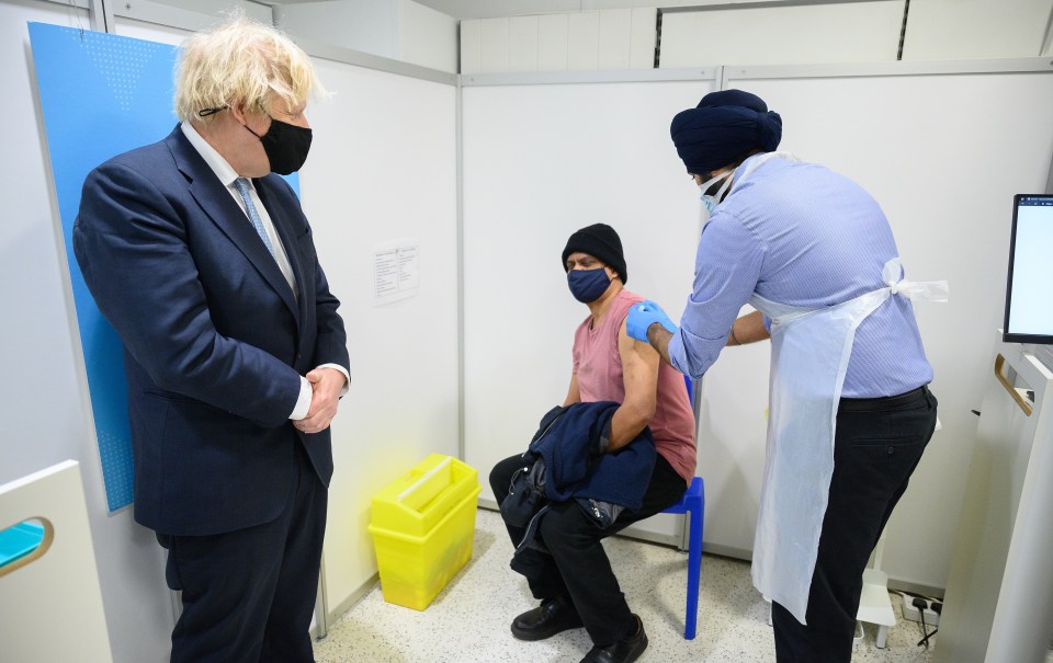 Boris Johnson watches someone get the vaccine on a trip to Boots in his local area