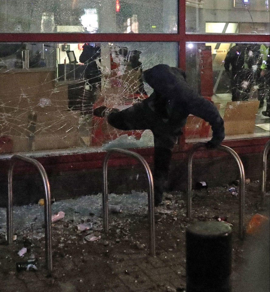 A protester kicks a smashed police station window during a 'Kill the Bill' protest