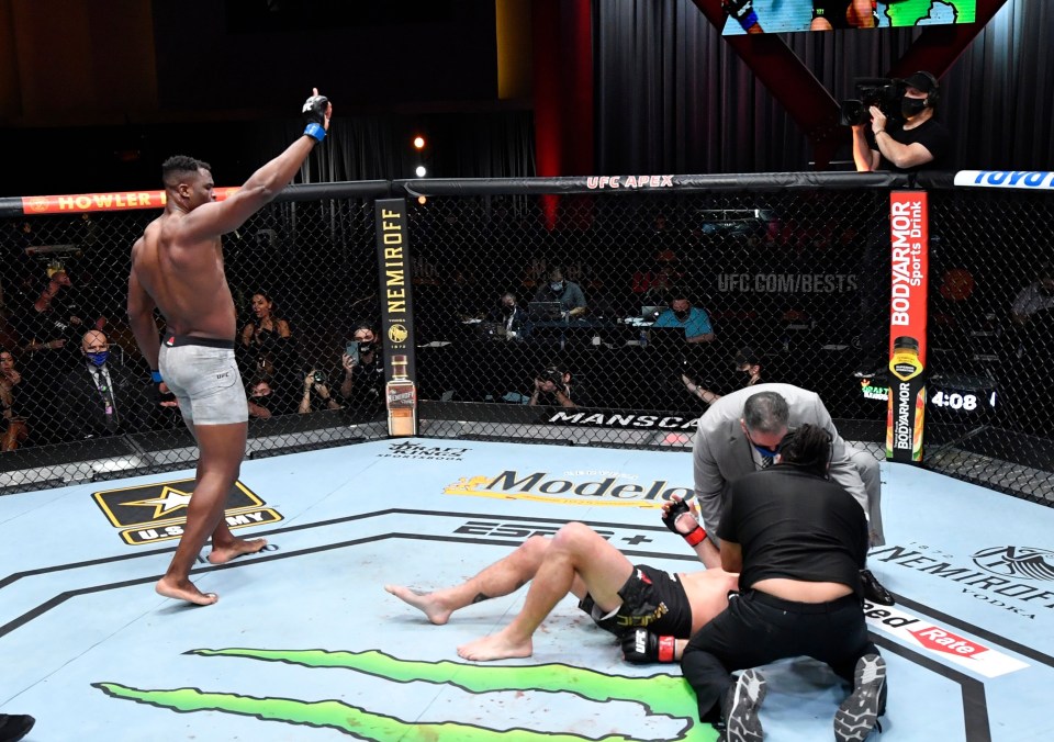 An elated Francis Ngannou celebrates as Stipe Miocic is tended to by the referee and the doctor