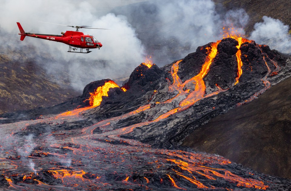 A chopper crew hover over rivers of boiling magma spewing from Mount Fagradalsfjall