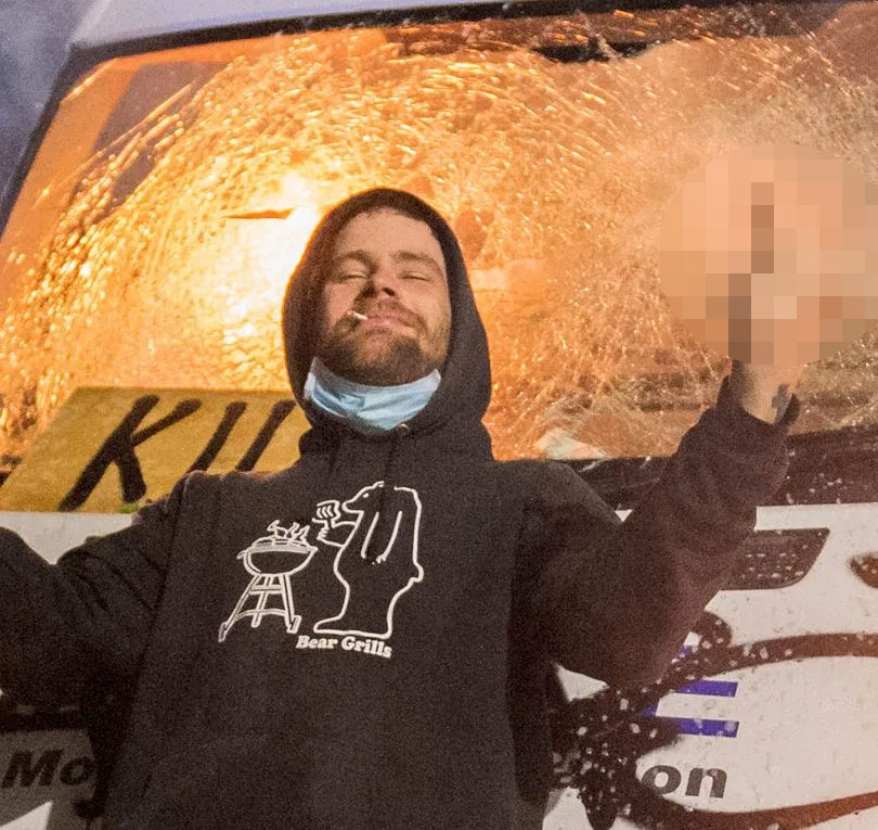 A man gestures as he stands in front of a police van