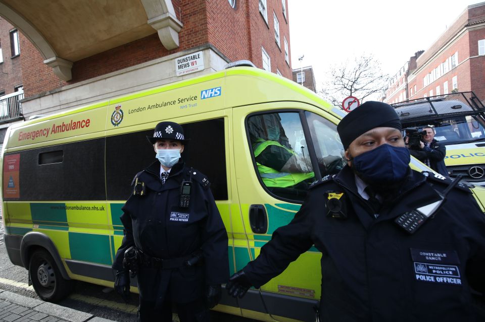 Police officers and security guards as the ambulance leaves the rear of the King Edward VII Hospital