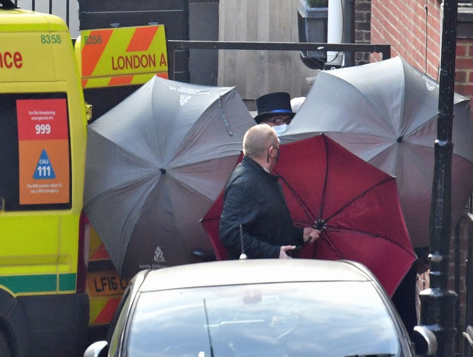 Staff shield the exit with umbrellas alongside an ambulance outside the rear of the King Edward VII Hospital in London where the Duke has spent 13 days