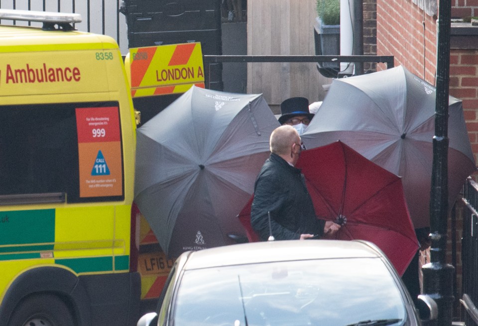 Staff shield the exit with umbrellas alongside an ambulance outside the rear of the King Edward VII Hospital in London where the Duke has spent 13 days