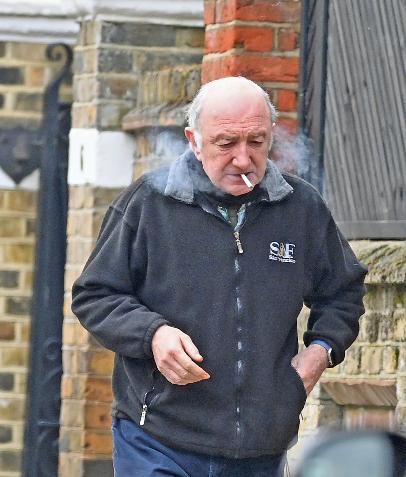 Queen bassist John Deacon puffs on a cigarette while out on a stroll in London