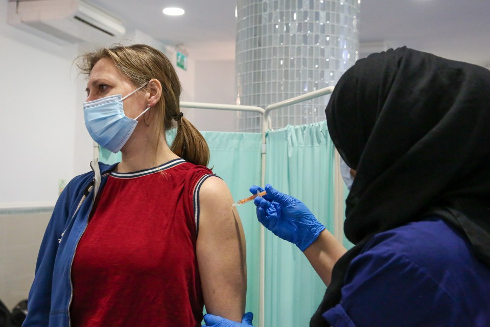 A NHS staff member administers the Oxford AstraZeneca vaccine