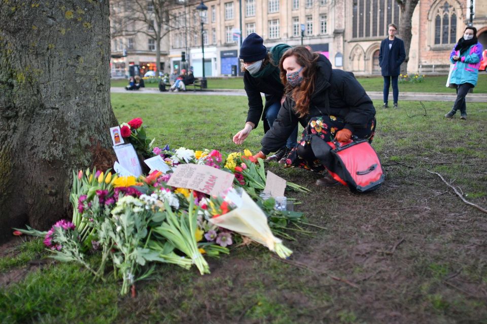 People places flowers at a tree on College Green in Bristol after the Reclaim These Streets vigil for Sarah Everard was officially cancelled