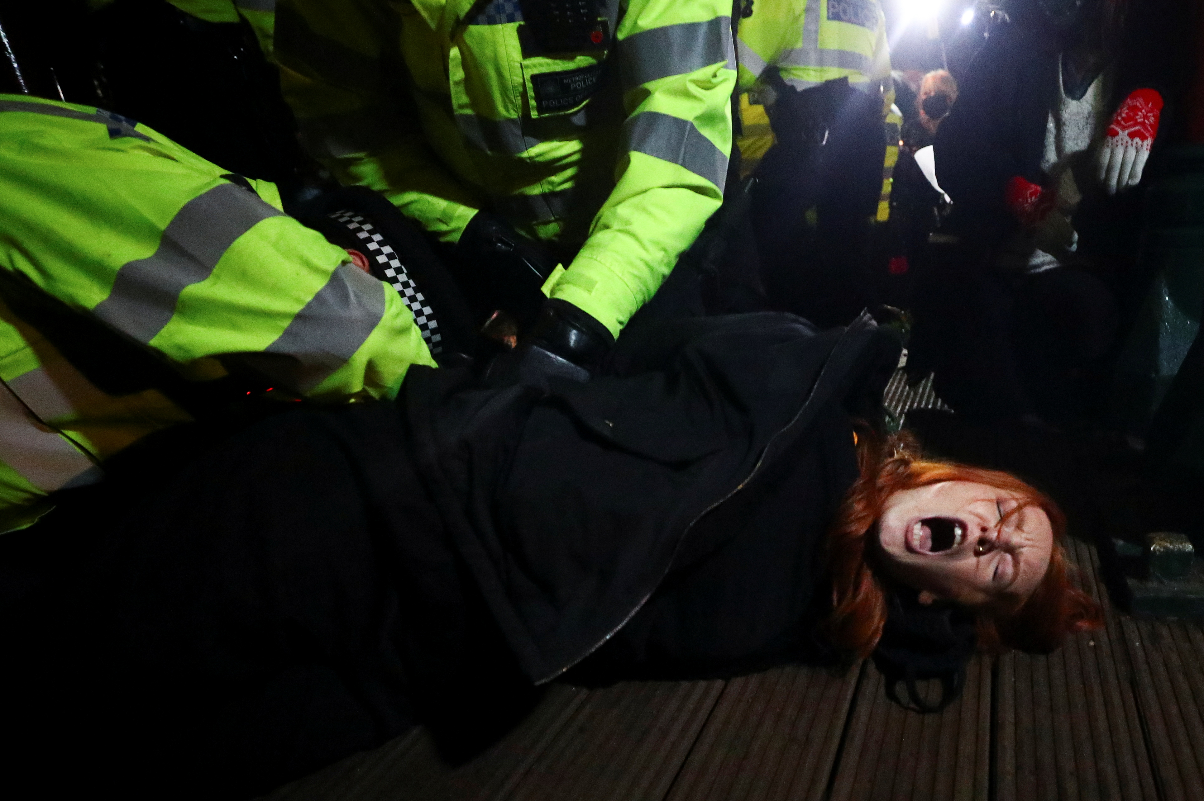 Police detain a woman as people gather at a memorial site in Clapham Common Bandstand