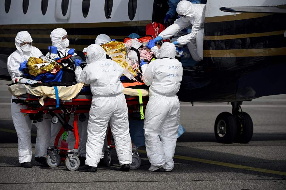 Medical staff carry a patient infected with Covid-19 from a medical plane to a helicopter as part of his transfer from Nice