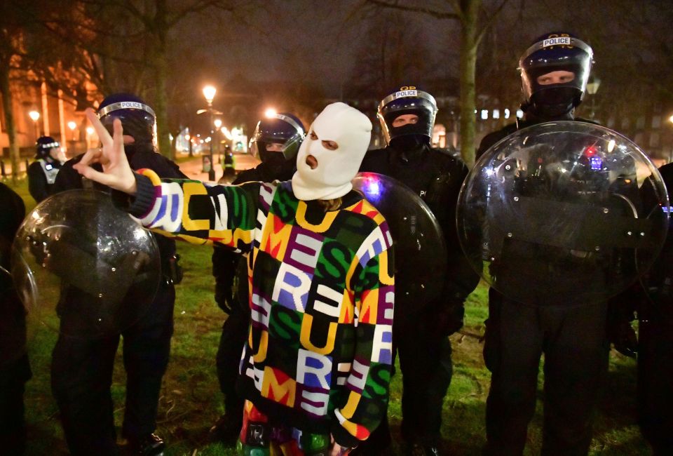 A masked protester poses in front of officers