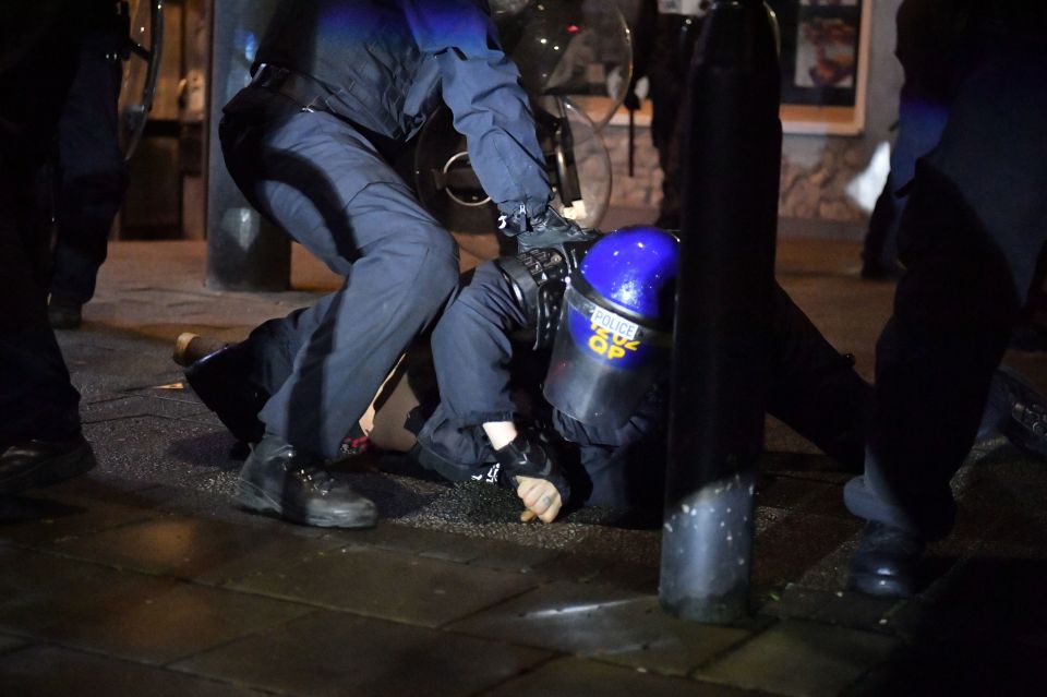 Police officers detain a man as they move in on demonstrators in Bristol