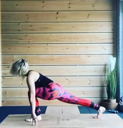 a woman is doing yoga on a yoga mat in front of a wooden wall .