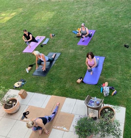 a group of women are doing yoga outside on a patio .