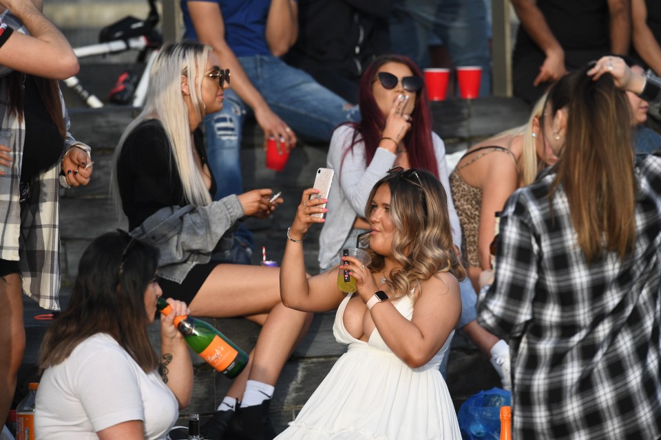 A woman takes a selfie as she enjoys a drink at Cardiff Bay, Wales