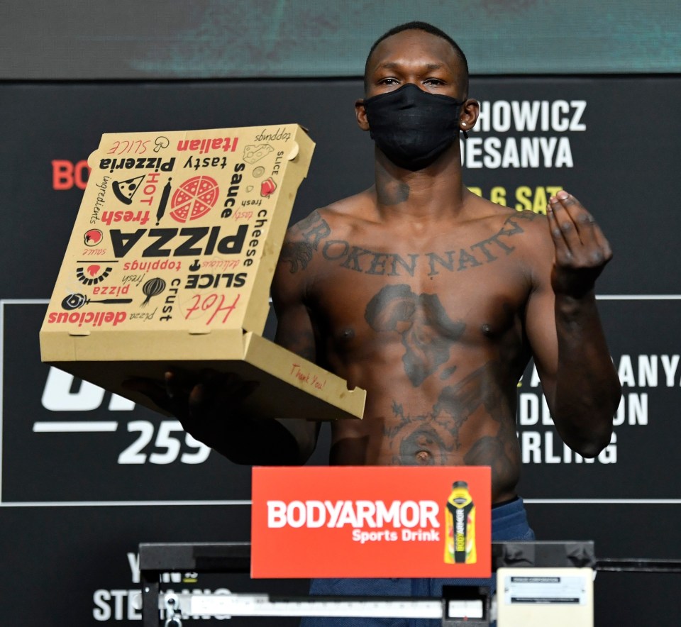 Israel Adesanya poses with a pizza box after successfully making weight