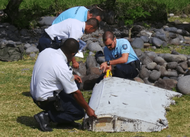 Cops inspect debris found on a beach on the Indian Ocean island of La Reunion