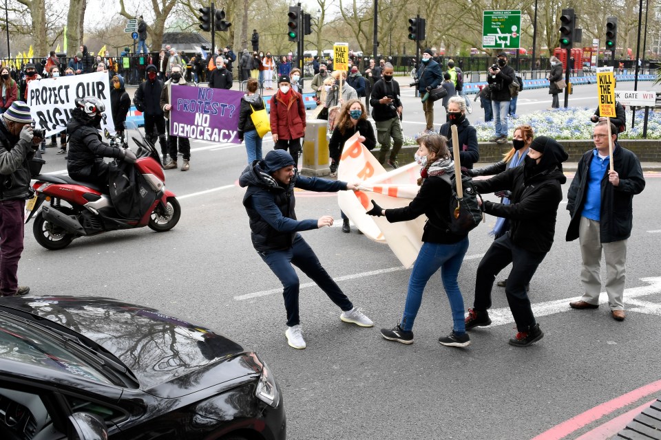 A man tries to rip a banner from protesters hands after blocking traffic in London