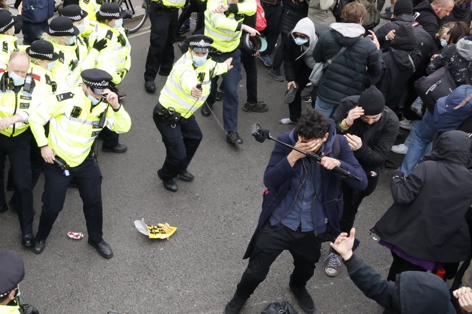 A police officer sprays pepper spray as scuffles break out in Parliament Square in central London