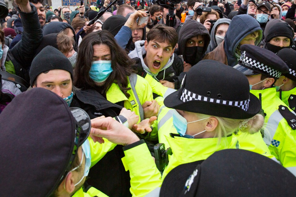 A police officer is punched in the face by a protesters in Parliament Square