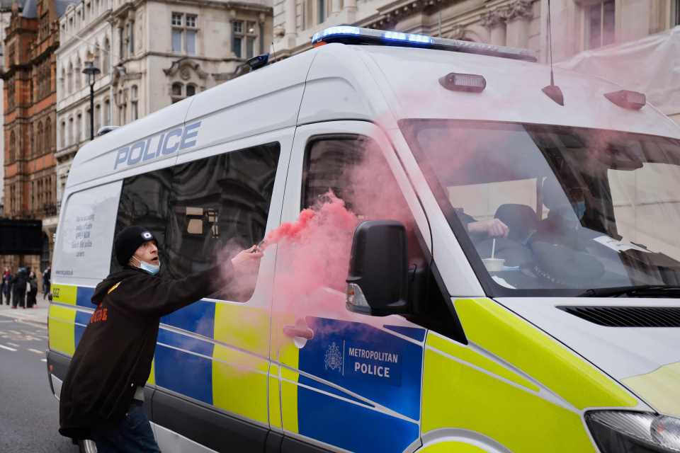 A demonstrator a smoke flare near the windows of a police van on Whitehall in central London