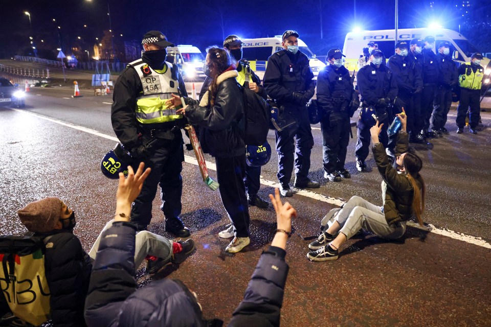 Demonstrators gesture as they block a motorway while police officers stand guard during a "Kill the Bill" protest in Bristol