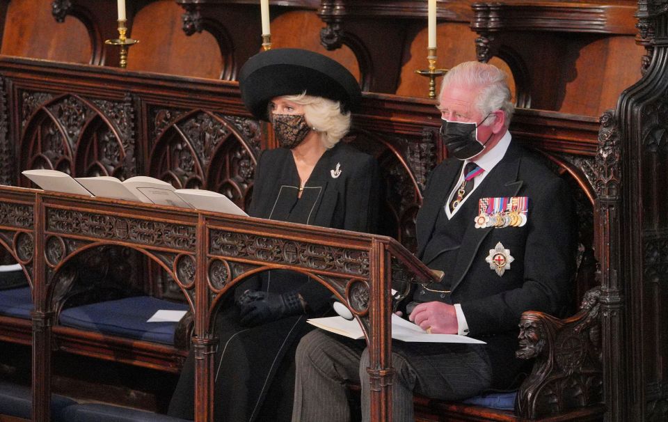 Prince Charles sits with his wife Camilla looking at his father's coffin