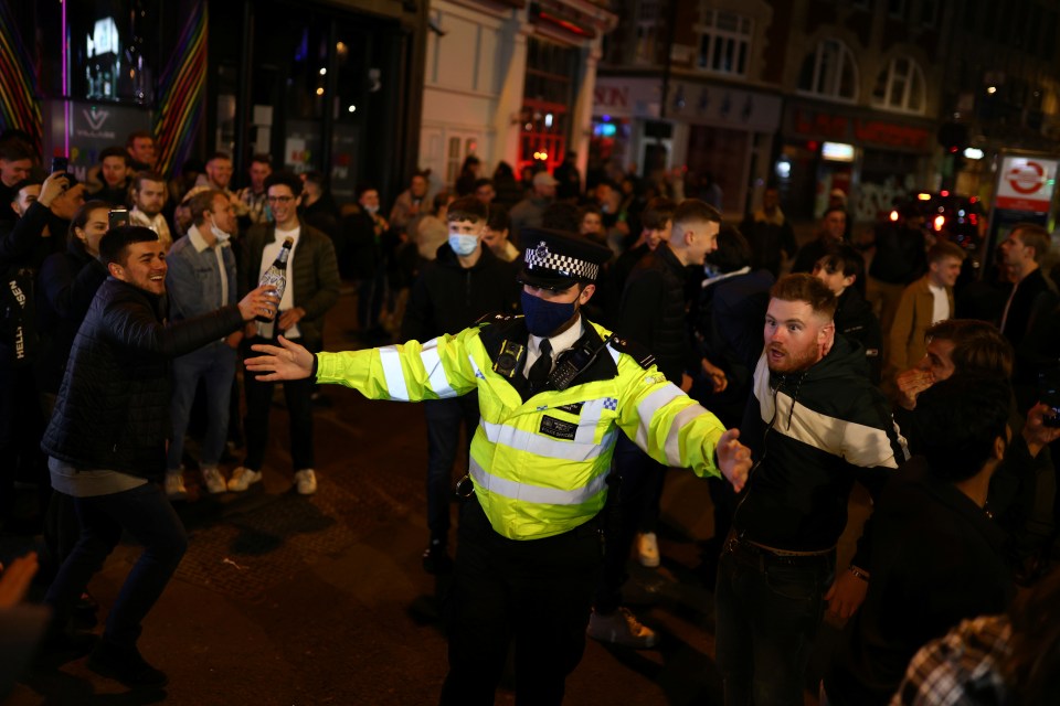 A copper gestures in the middle of a lively crowd