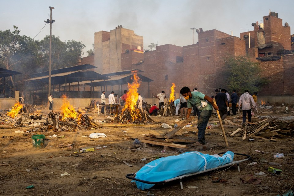 A man prepares a funeral pyre to cremate the body of a person who died due to coronavirus disease