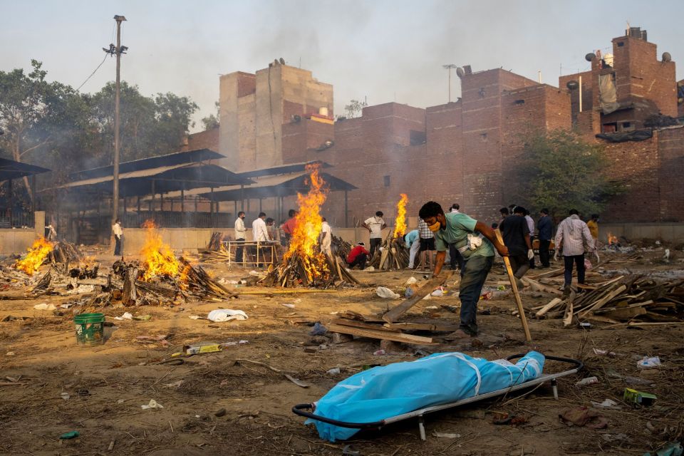 A man prepares a funeral pyre to cremate the body of a person who died due to coronavirus disease