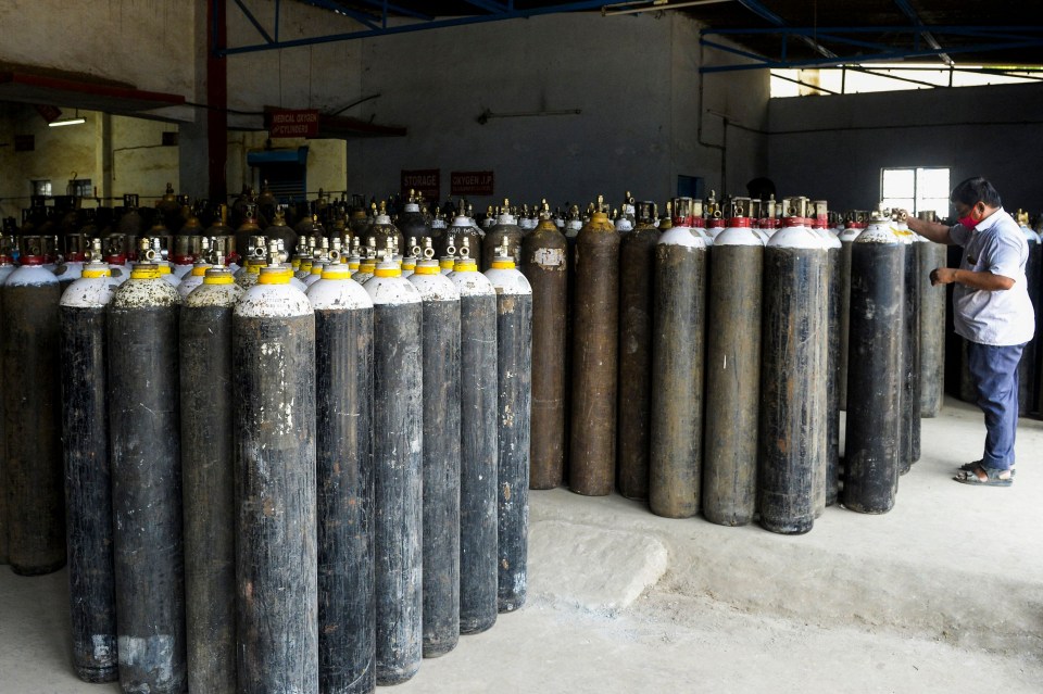 A worker arranges medical oxygen cylinders to be transported to hospitals on the outskirts of Hyderabad