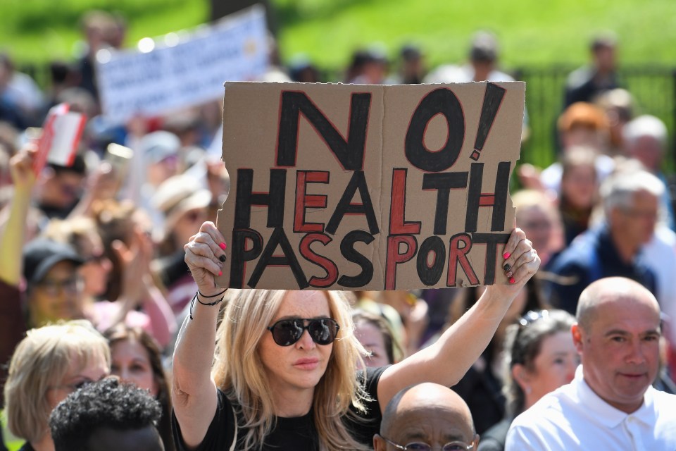 A woman holds a sign against Covid health passports