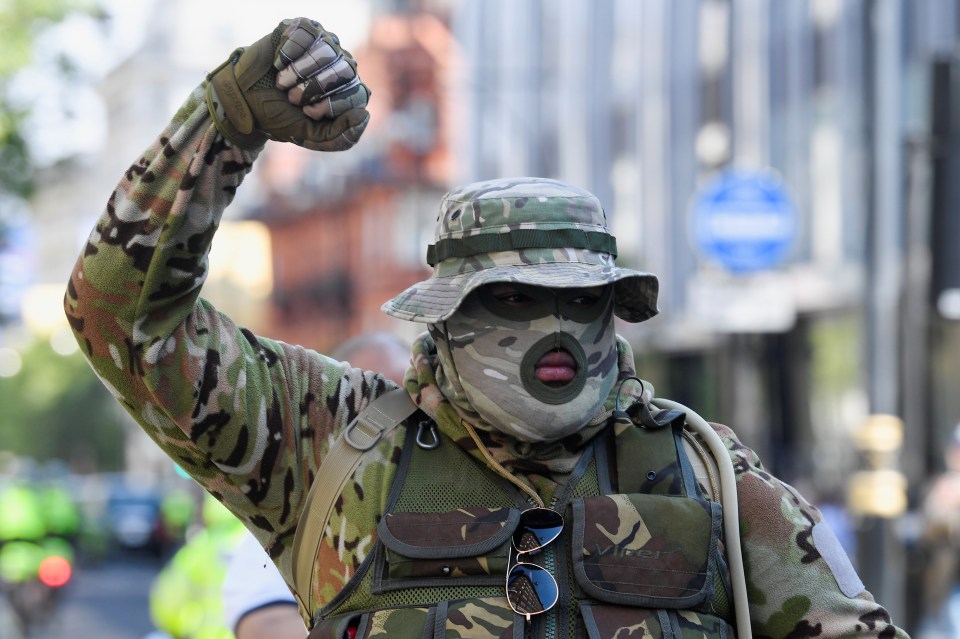 A demonstrator dressed in camouflage raises a fist during the protest