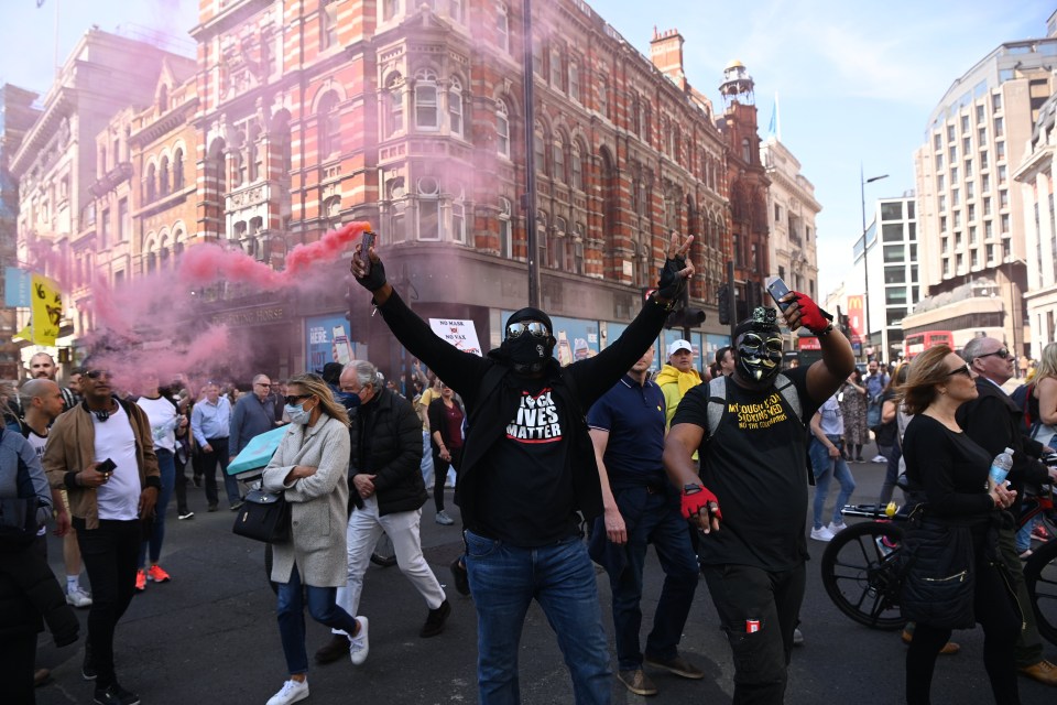 An anti-vaccination and anti-lockdown protester lets off another smoke flare