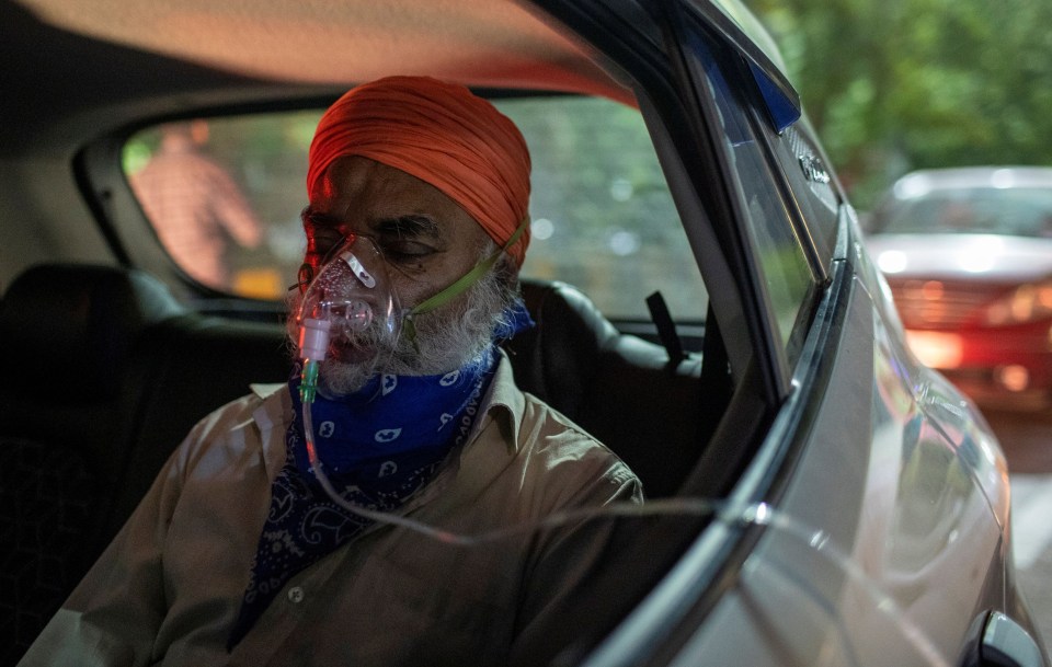 A man sitting in his car gets oxygen supplied outside a Sikh temple