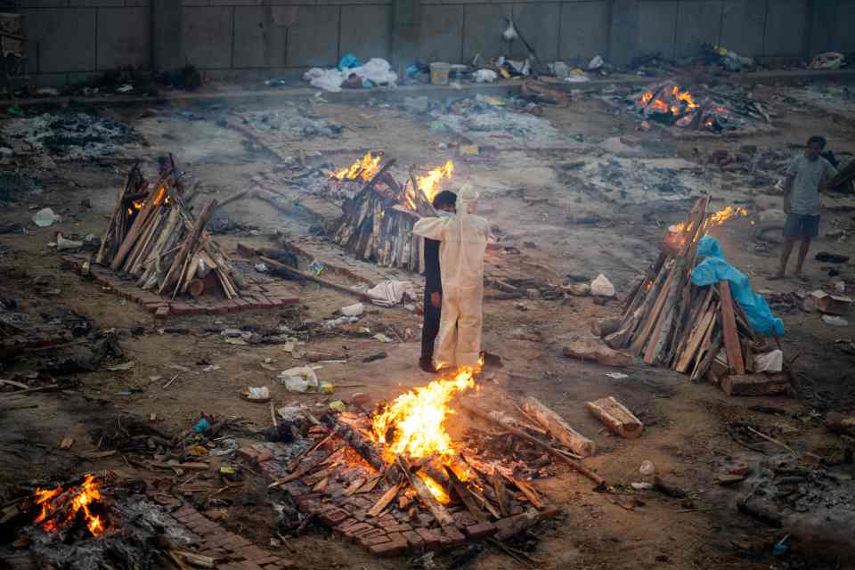 A worker comforts the relative of one Covid victim at a cremation ground