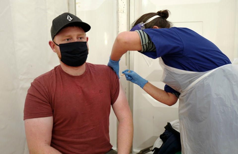 A man working for Age UK receives the AstraZeneca vaccine