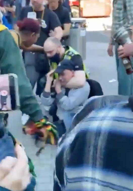 A man is headlocked by a police officer outside the shopping centre