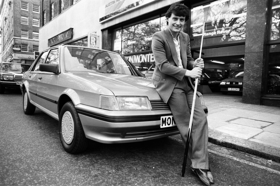 White poses beside a new model Austin Montego in 1984