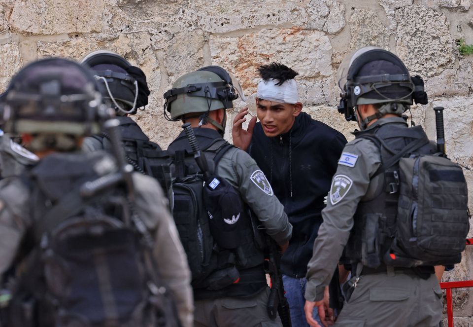 A wounded Palestinian protester is surrounded by Israeli riot policemen during clashes at the entrance of Jerusalem's Old City, May 2021