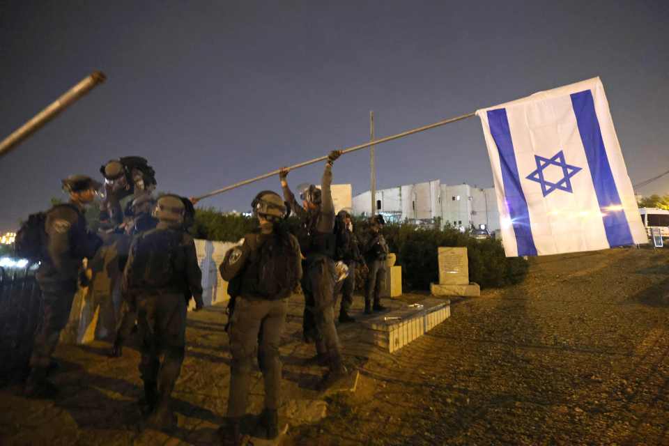 Israeli border police put back an Israeli flag after it was taken down by Palestinian protesters in east Jerusalem