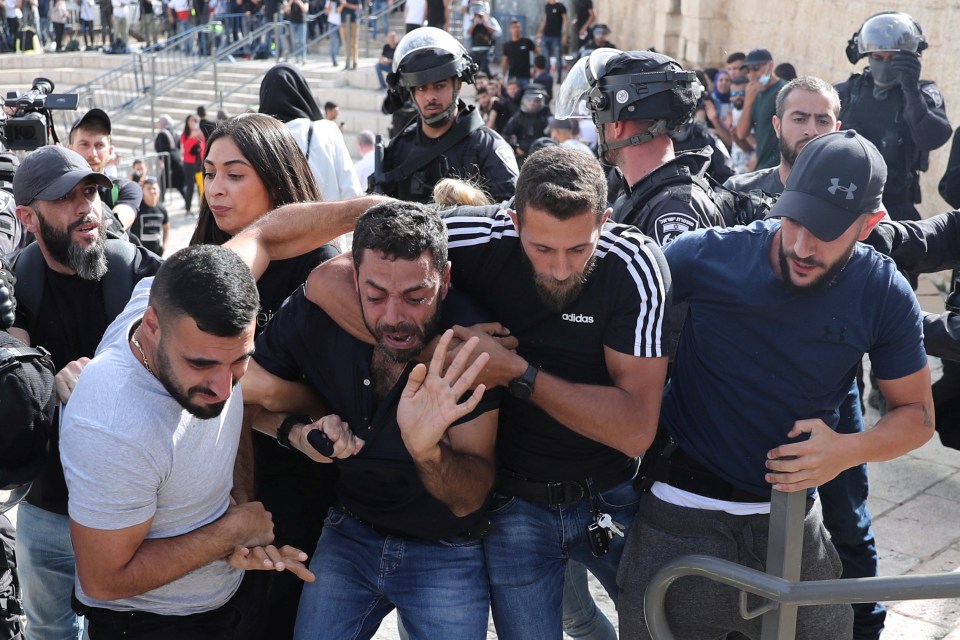 A Palestinian man reacts as he is detained by undercover Israeli security force members amid Israeli-Palestinian tension