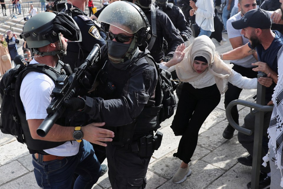 A woman runs past Israeli cops during scuffles at Damascus Gate just outside Jerusalem's Old City