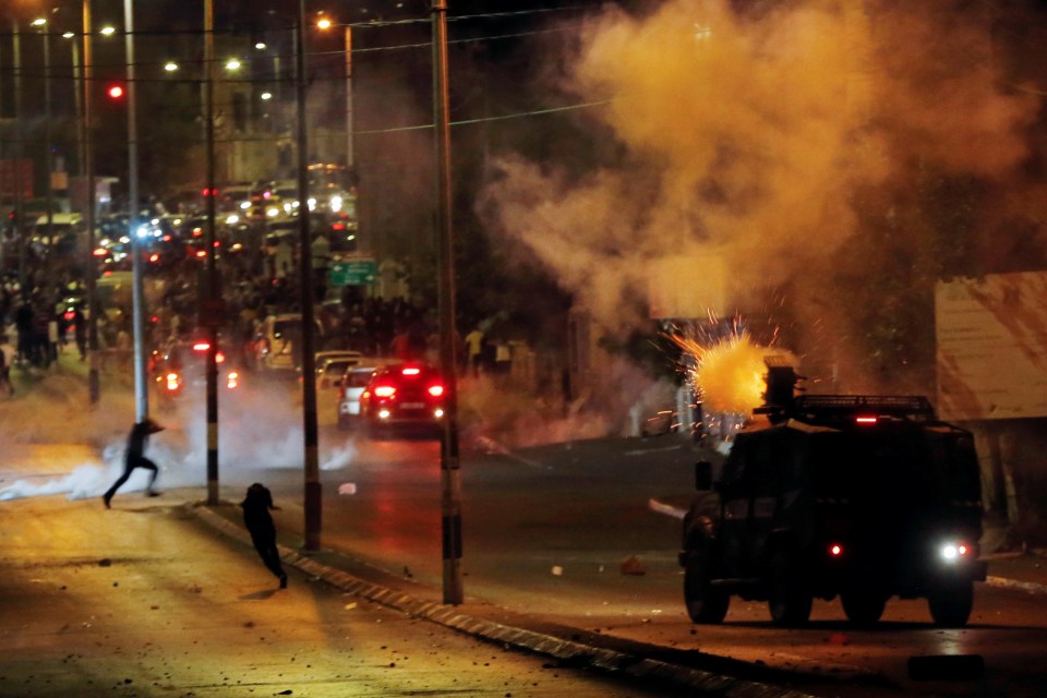 Palestinians run as Israeli military vehicle fires tear gas canisters during a protest in Bethlehem